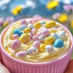 A vibrant bowl of Easter dip swirled in pastel colors, topped with candy eggs and rainbow sprinkles